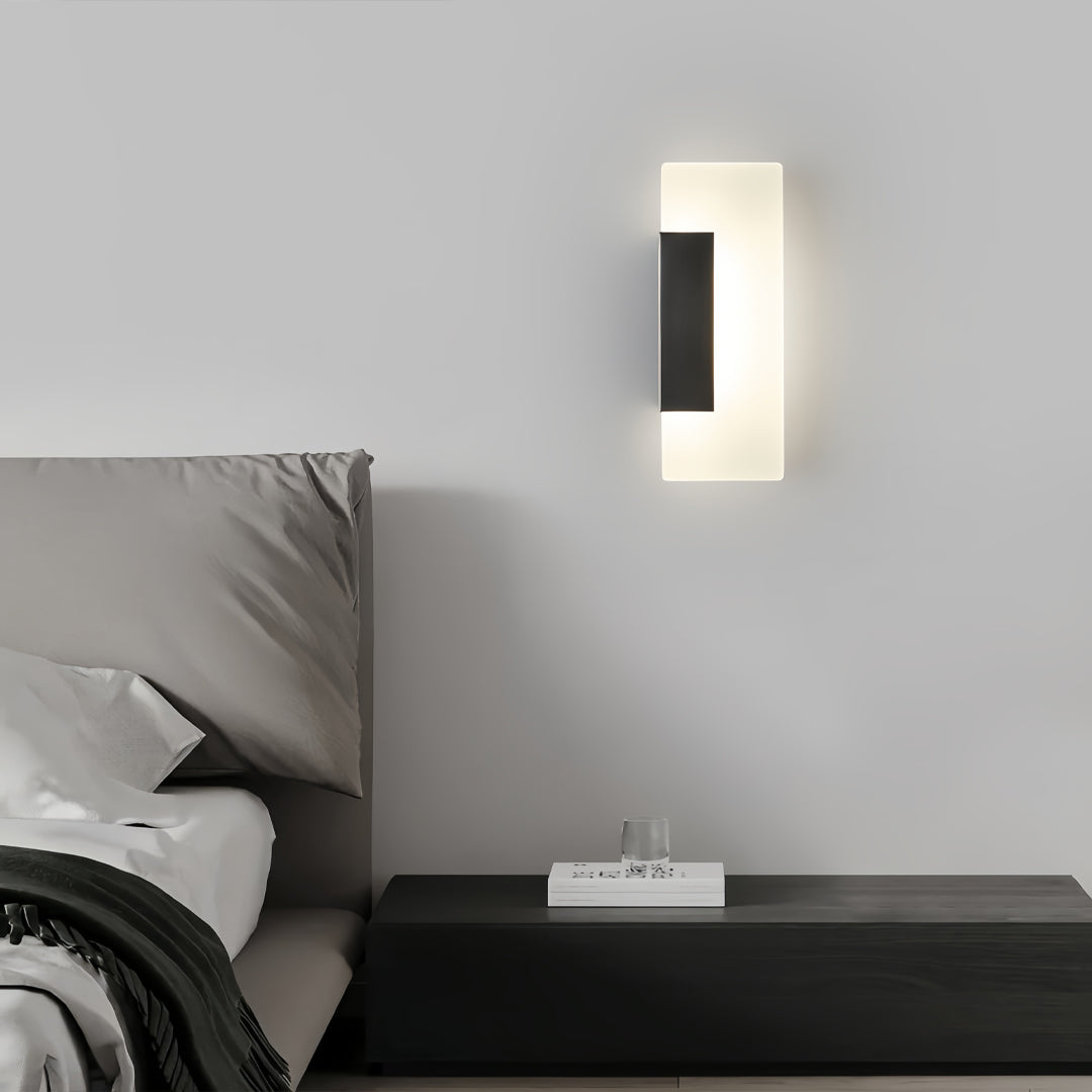 Brass wall lights providing ambient bedside illumination in modern bedroom with black platform bed and gray walls