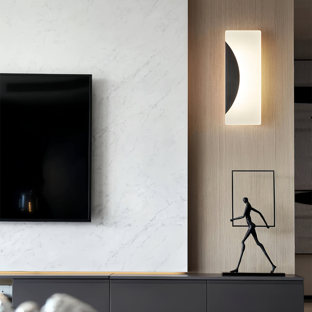 Brass wall lights illuminating hallway with black framed artwork and natural wood architectural details