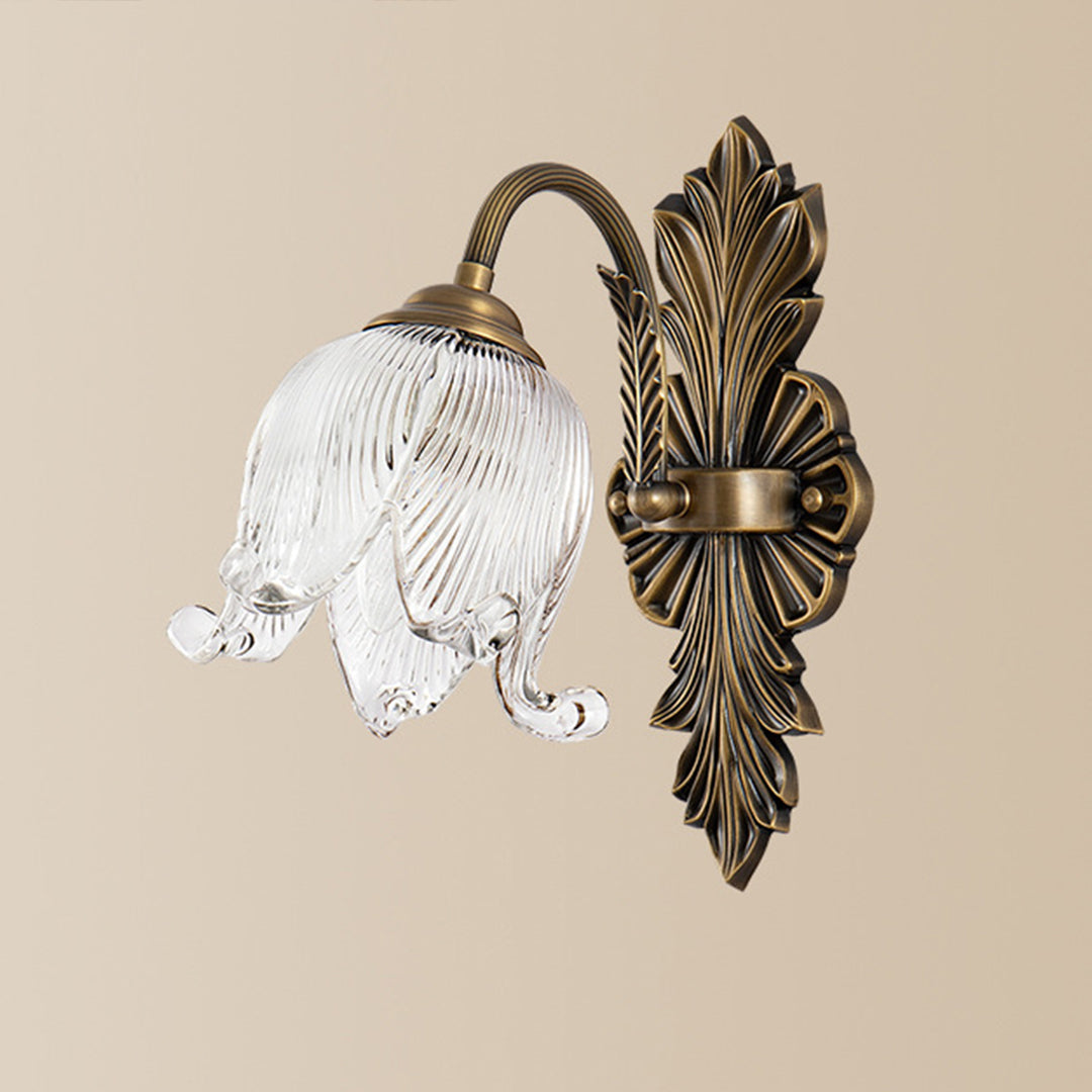 Single brass wall lights with ornate backplate illuminating minimalist wall with round mirror