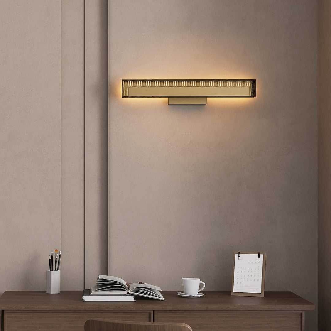 Warm brass wall picture light mounted above desk, adding soft ambient glow.
