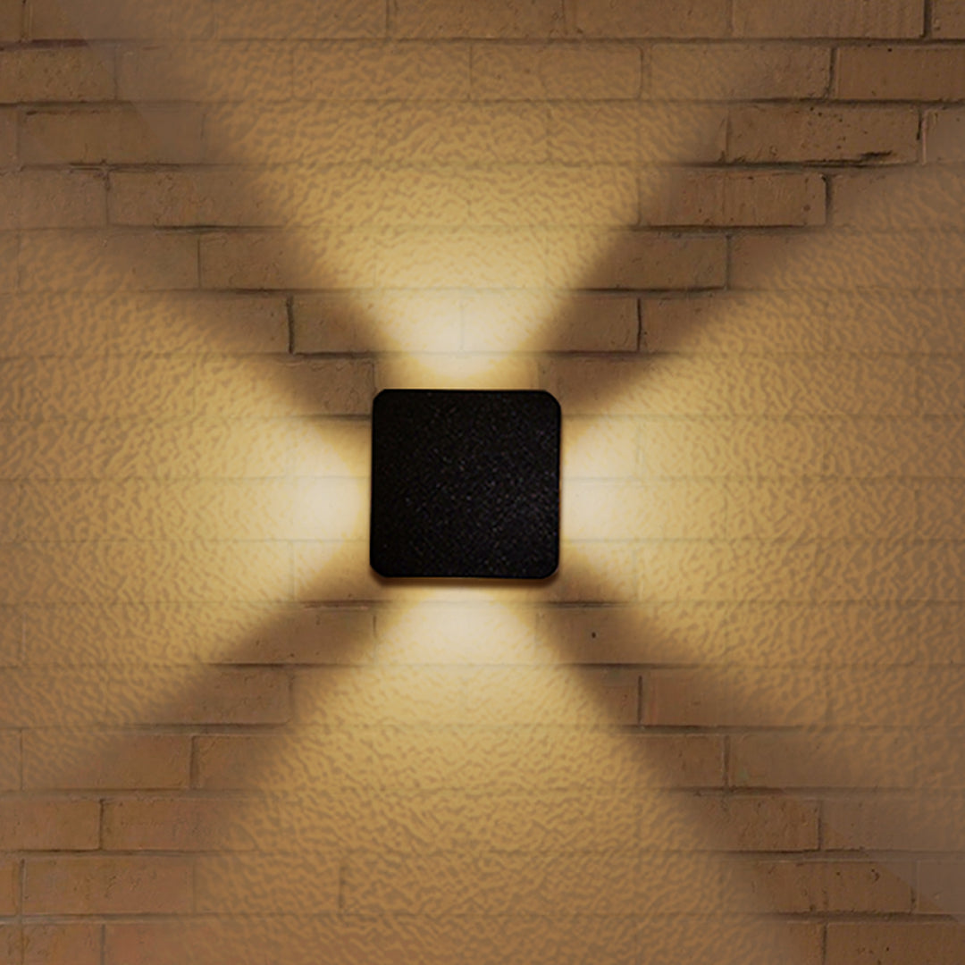 Textured brick wall illuminated by cross-pattern LED fixture creating dramatic architectural lighting effects