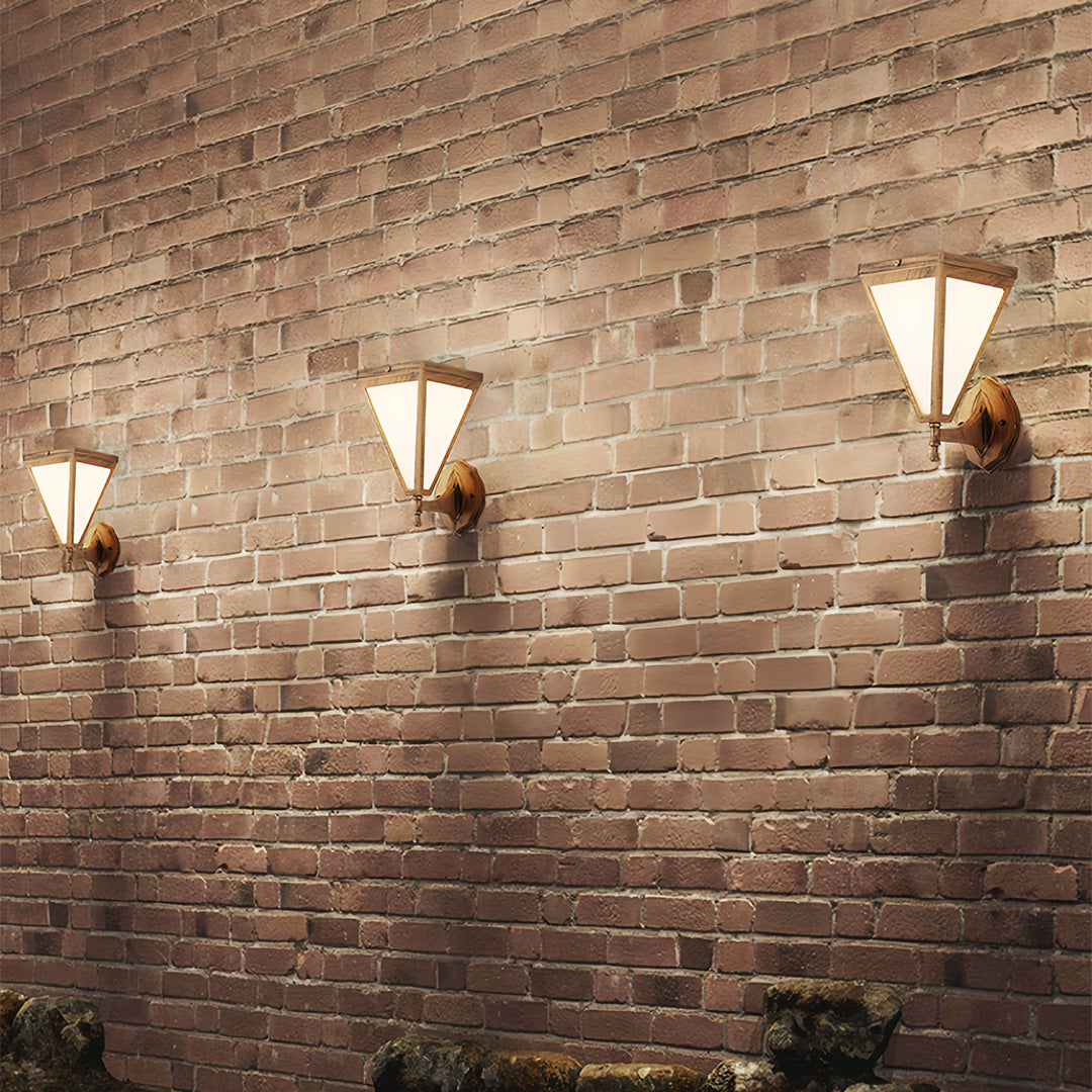 Outdoor solar lights wall mounted on brick wall arranged in a triple-light setup.
