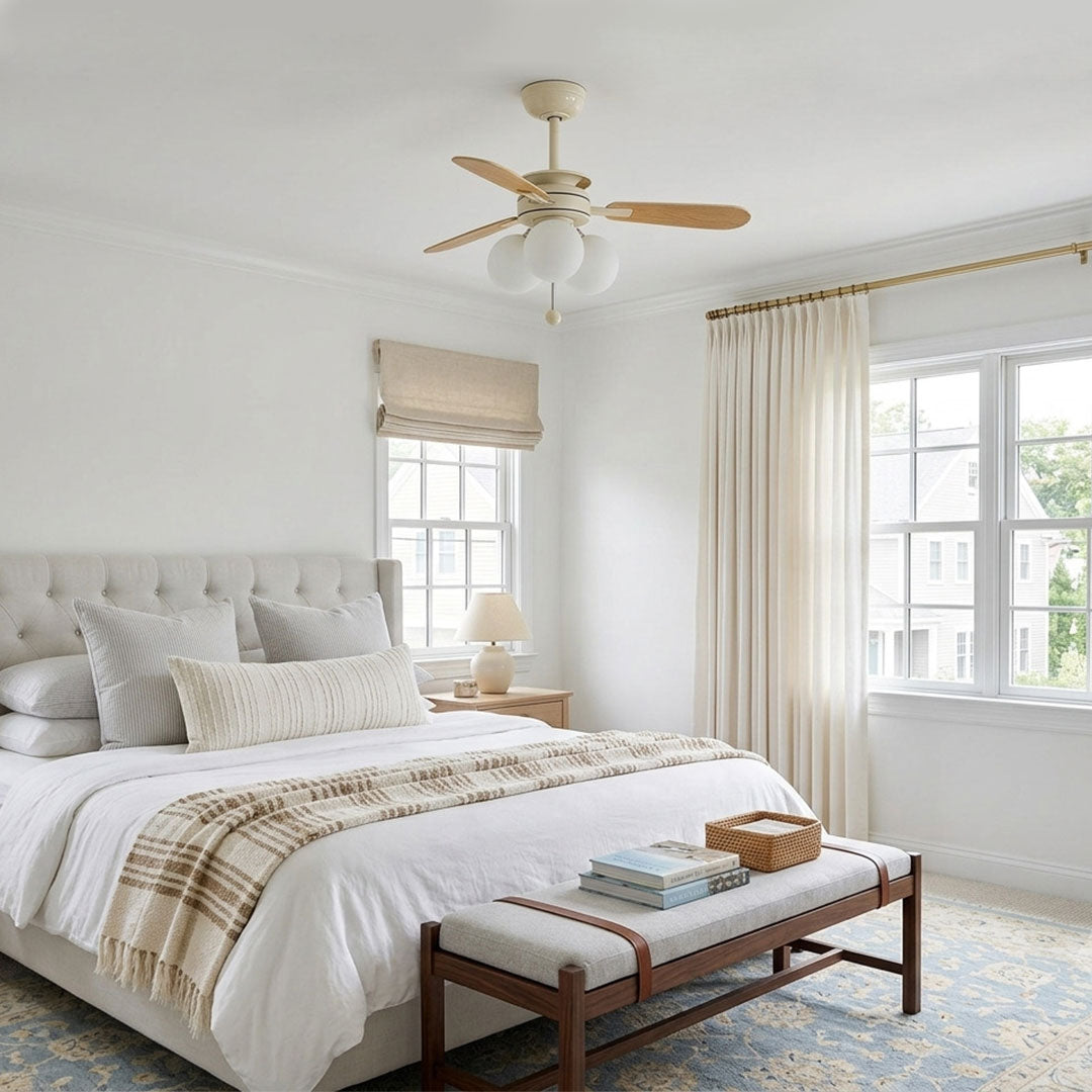 Indoor ceiling fan with light installed in a bright bedroom with cream hardware and wood blades.