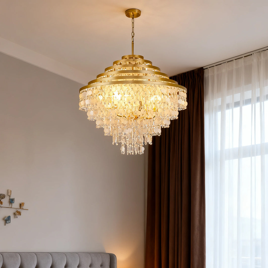 Modern gold-tiered crystal chandelier with hanging shells in a cozy living room