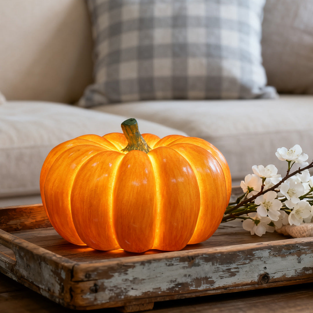 Single bright halloween pumpkin light glowing warmly on a wooden tray in a living room.