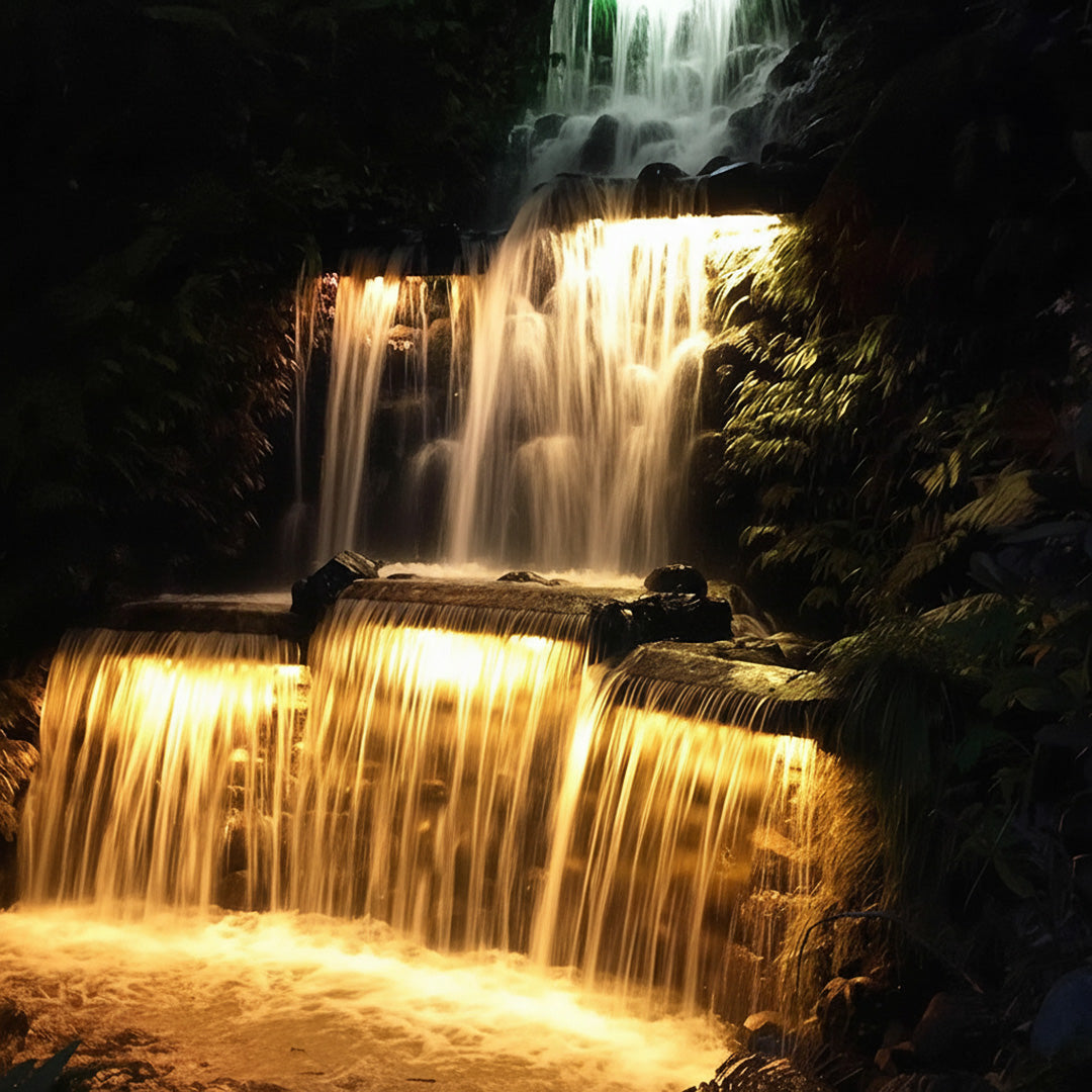 The bright linear wall washer light gives a warm golden glow to a stunning rocky waterfall.