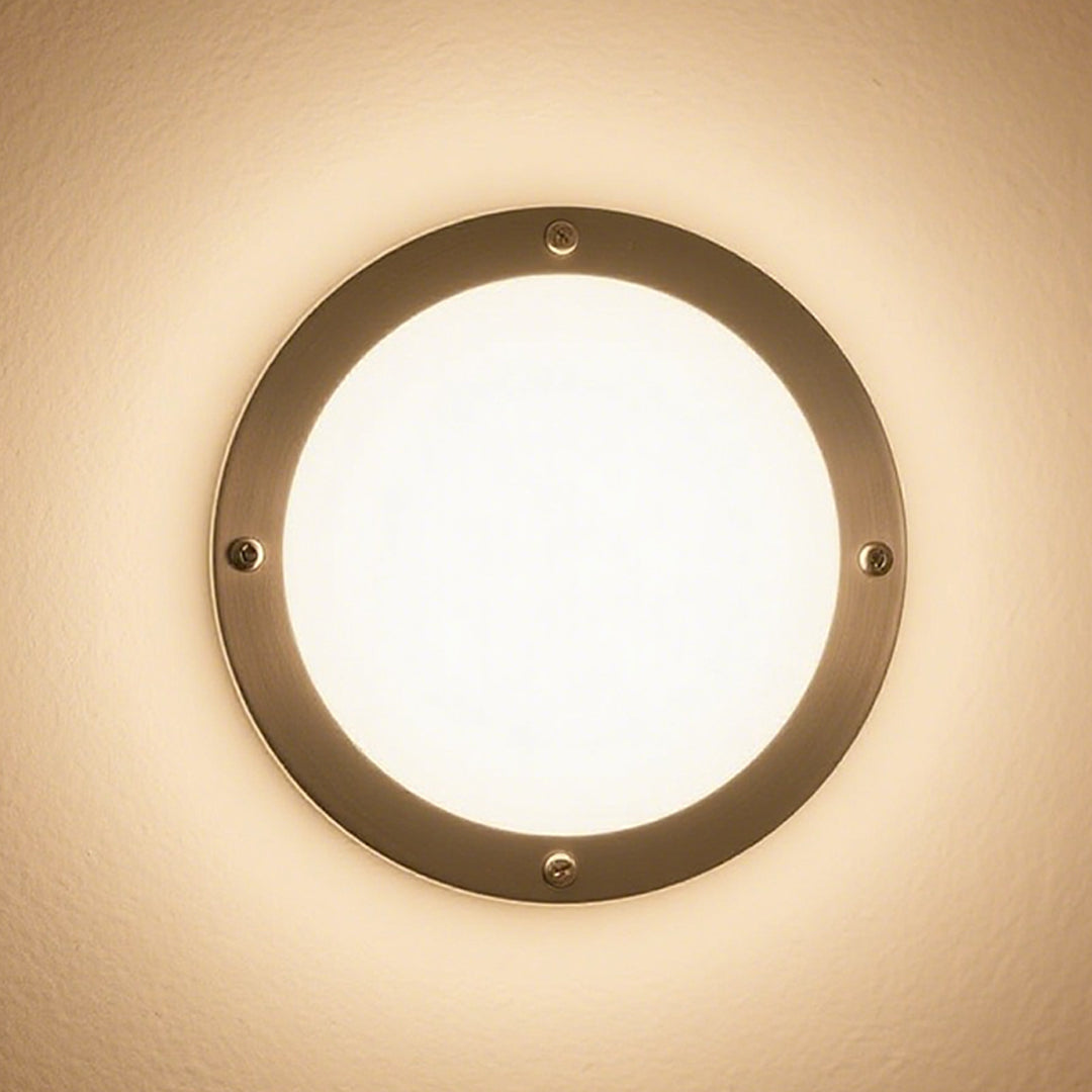 Close-up of a brightly lit round outdoor wall lights fixture with a brushed metal bezel, casting a warm glow.