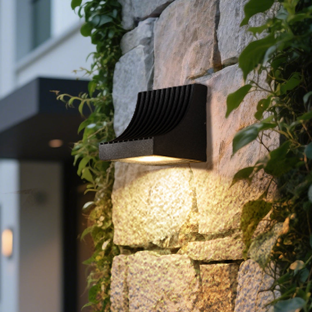 Traditional brass wall lantern with frosted glass shade mounted on stone exterior wall