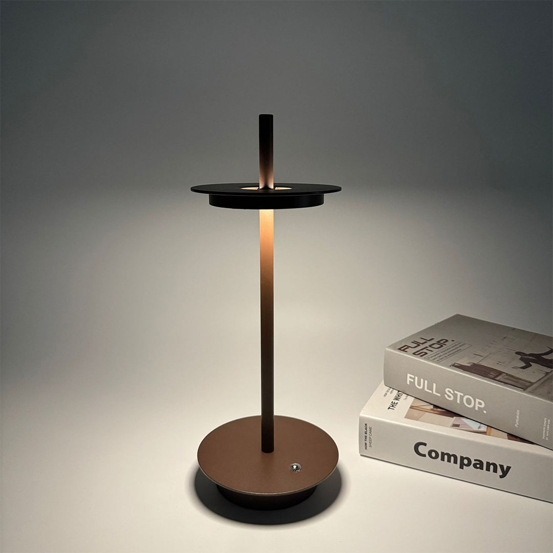 Warm dimmable table lamp with bronze finish creating intimate lighting next to office materials