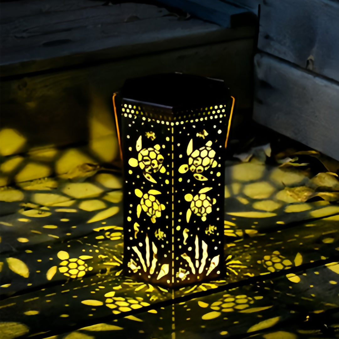 Bronze-finish red outdoor lantern showing tortoise and honeycomb cutouts creating warm ground light.