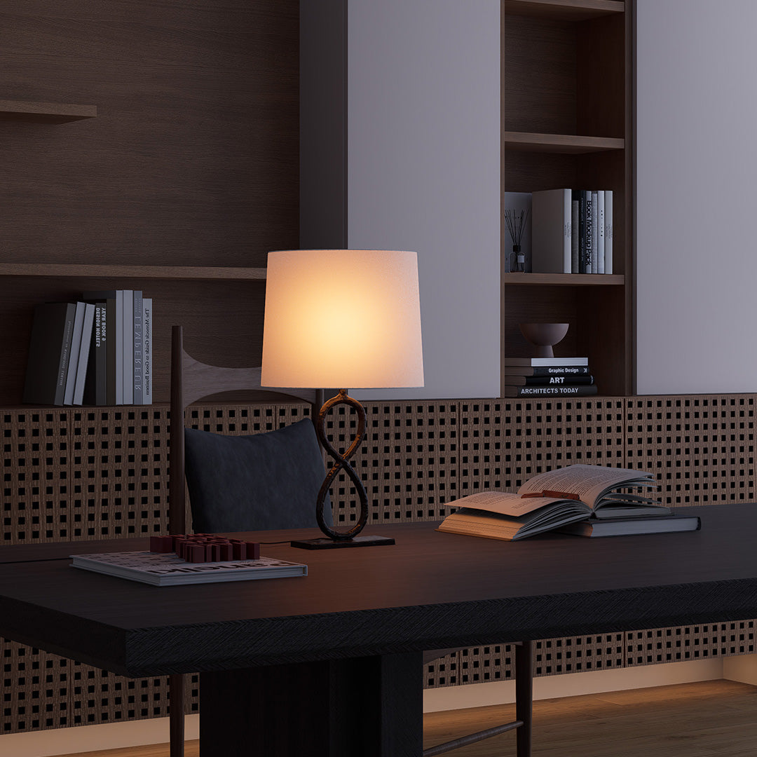 Bronze metal table lamp with linen shade on black office desk, adding cozy glow.