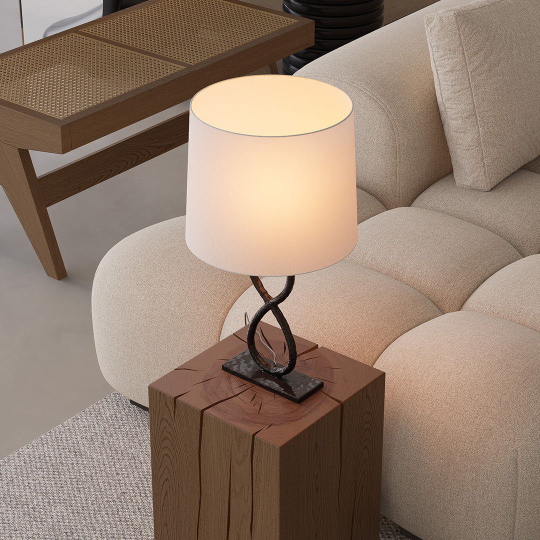 Contemporary bronze metal table lamps on wooden side table beside sofa, softly illuminating living room.