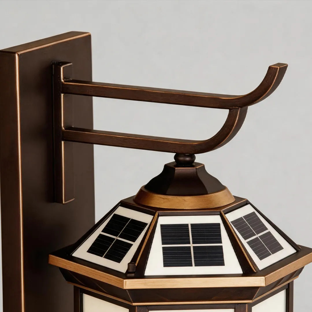 Bronze outdoor sconce detail showing the mounting arm, backplate, and solar panel top structure.