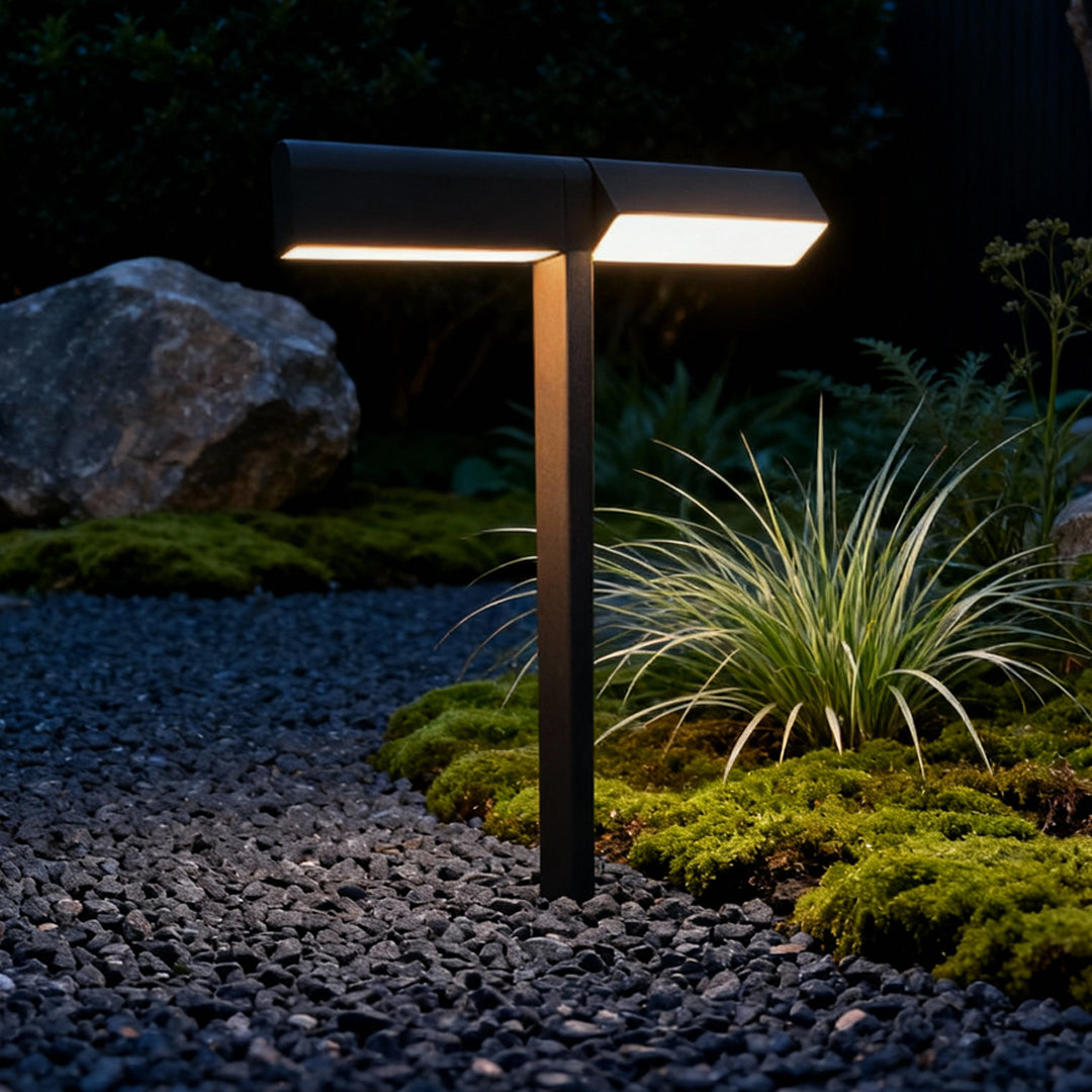 Tall bronze-finish pathway lamp illuminating plants and gravel at night, creating elegant led pathway lighting.