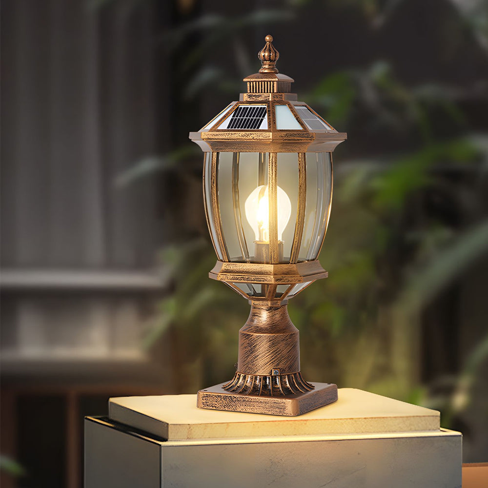 Illuminated bronze pedestal lantern creating warm ambient lighting on outdoor stone surface at evening