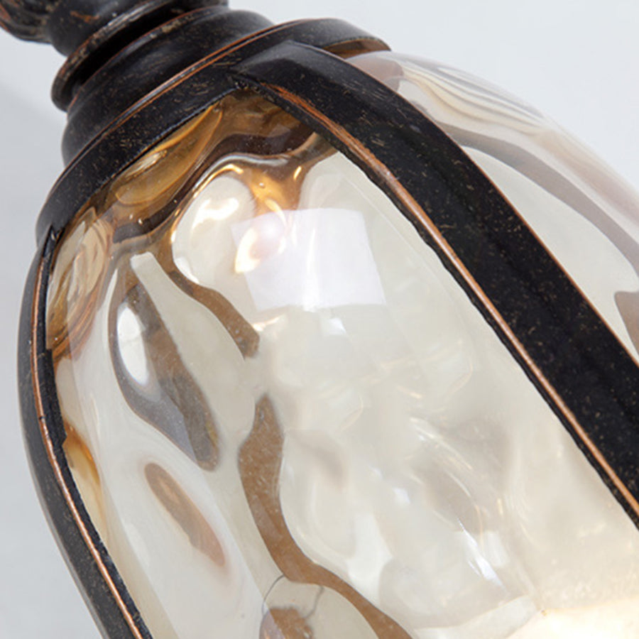 Elegant bronze outdoor sconce with textured glass panel and warm interior illumination