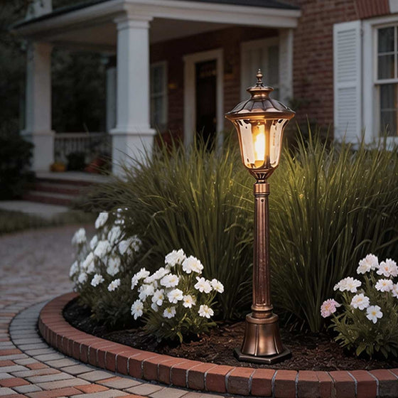 Bronze street lamp illuminating a classic garden pathway with warm ambient glow.
