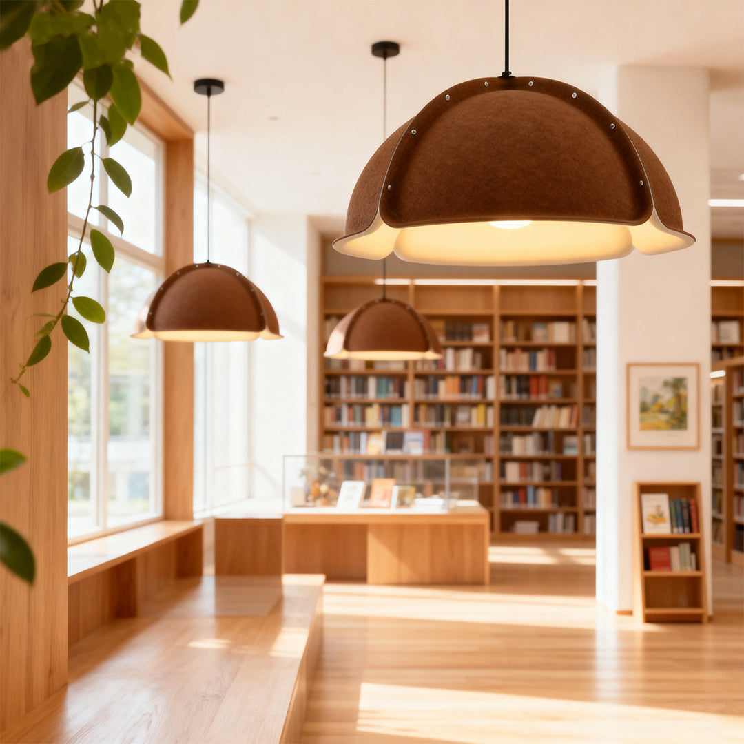 Two large brown dome colored pendant light fixtures illuminating a minimalist public reading area with full-length windows.
