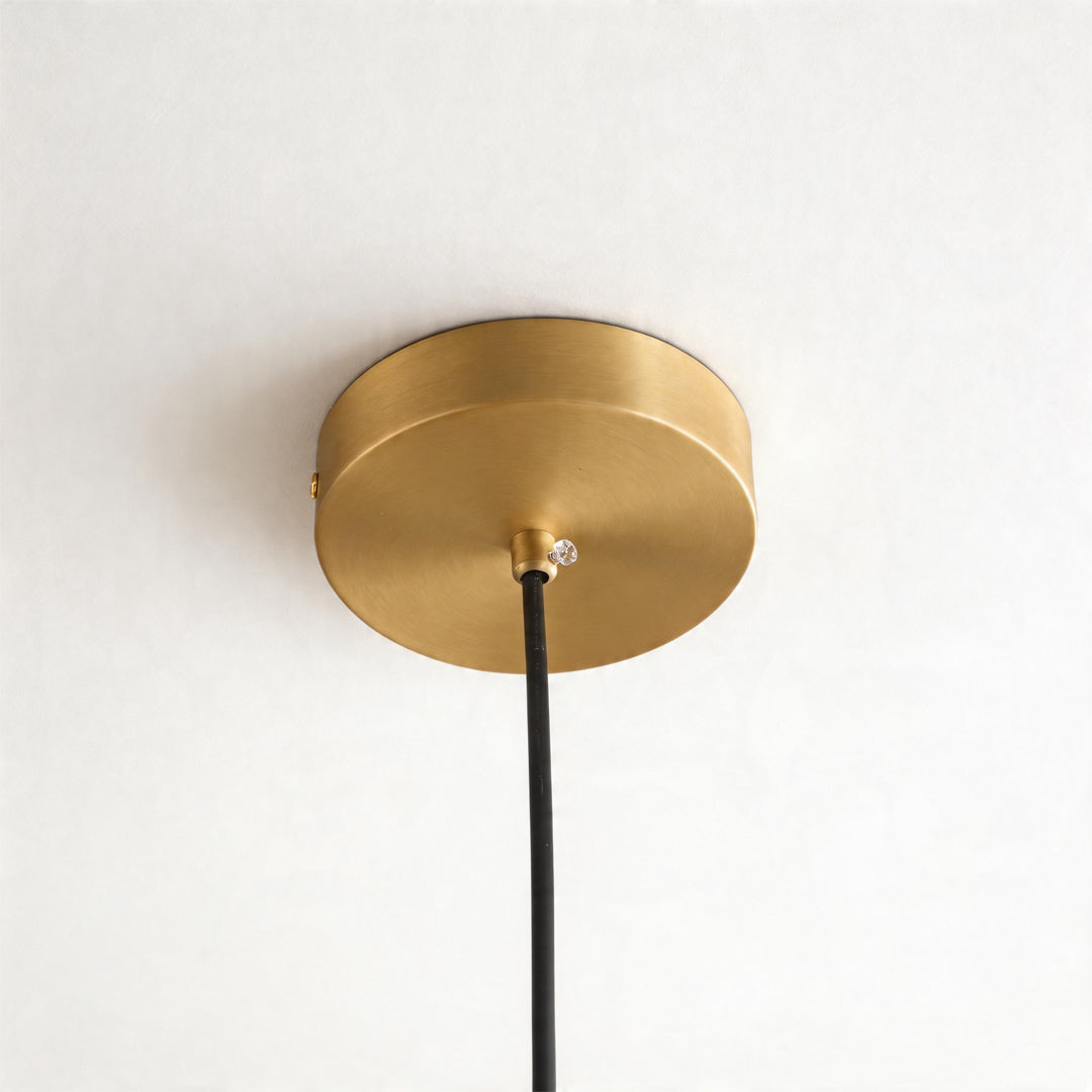 Close up of the brushed gold ceiling canopy for a brass pendant lighting fixture with a cord.
