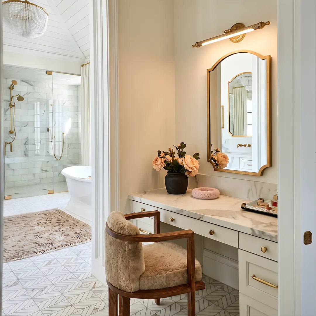 Brushed gold vanity light bar installed above a mirror in a bright bathroom vanity and makeup area.