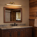Brushed gold vanity light bar mounted above a rustic bathroom mirror