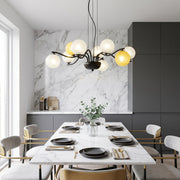 Bubble chandelier lighting with glass globe shades installed above a modern dining table in a marble kitchen setting.