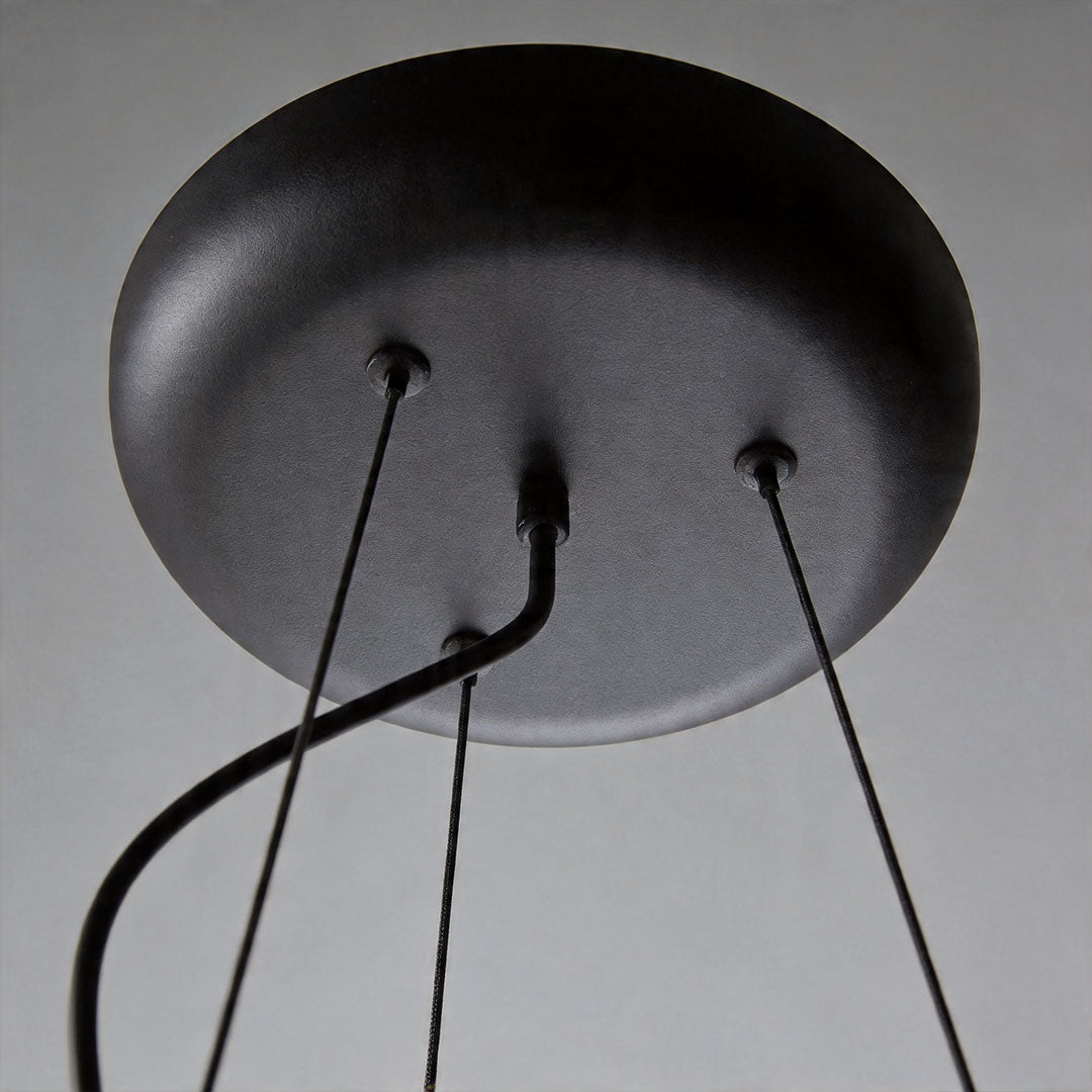 Close-up of black ceiling canopy and suspension wires of bubble glass chandelier fixture.