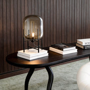 Bubble glass floor lamp with a sleek black metal frame, placed beside a wooden table and books.