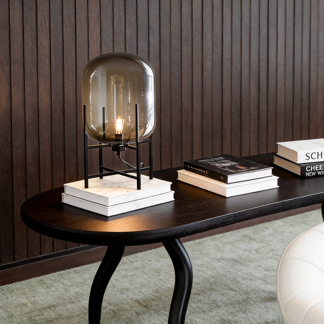 Bubble glass floor lamp with a sleek black metal frame, placed beside a wooden table and books.