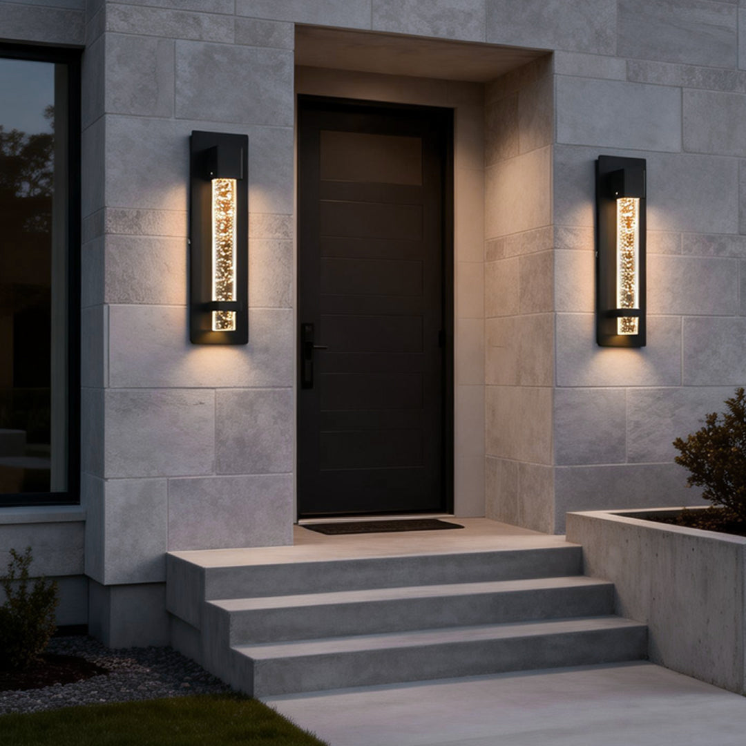 Tall bubble wall sconce lighting a home entrance, highlighting stone facade with soft ambient glow at dusk.