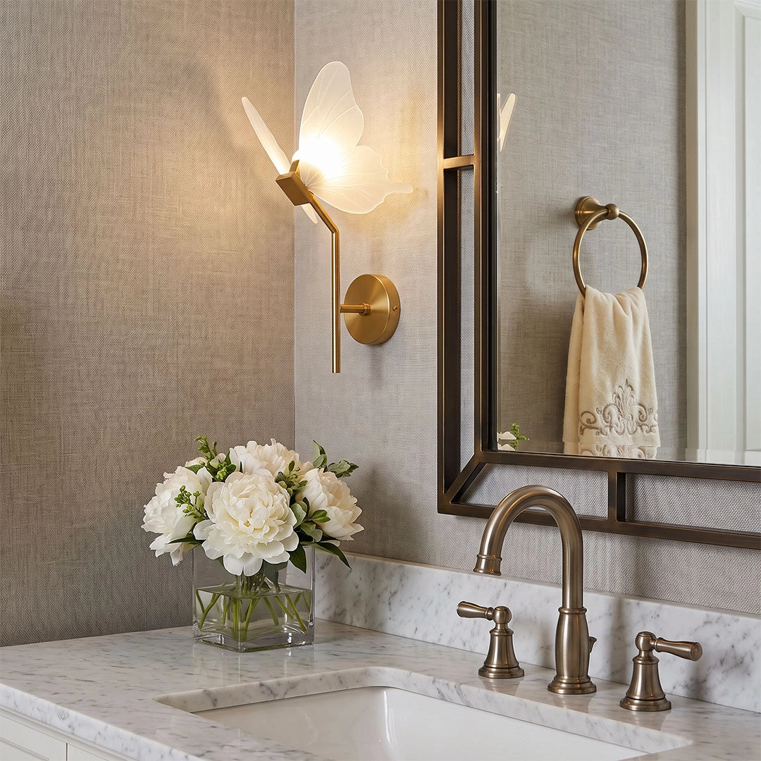 Butterfly wall light above a bathroom vanity with a brass finish and softly glowing translucent wings.