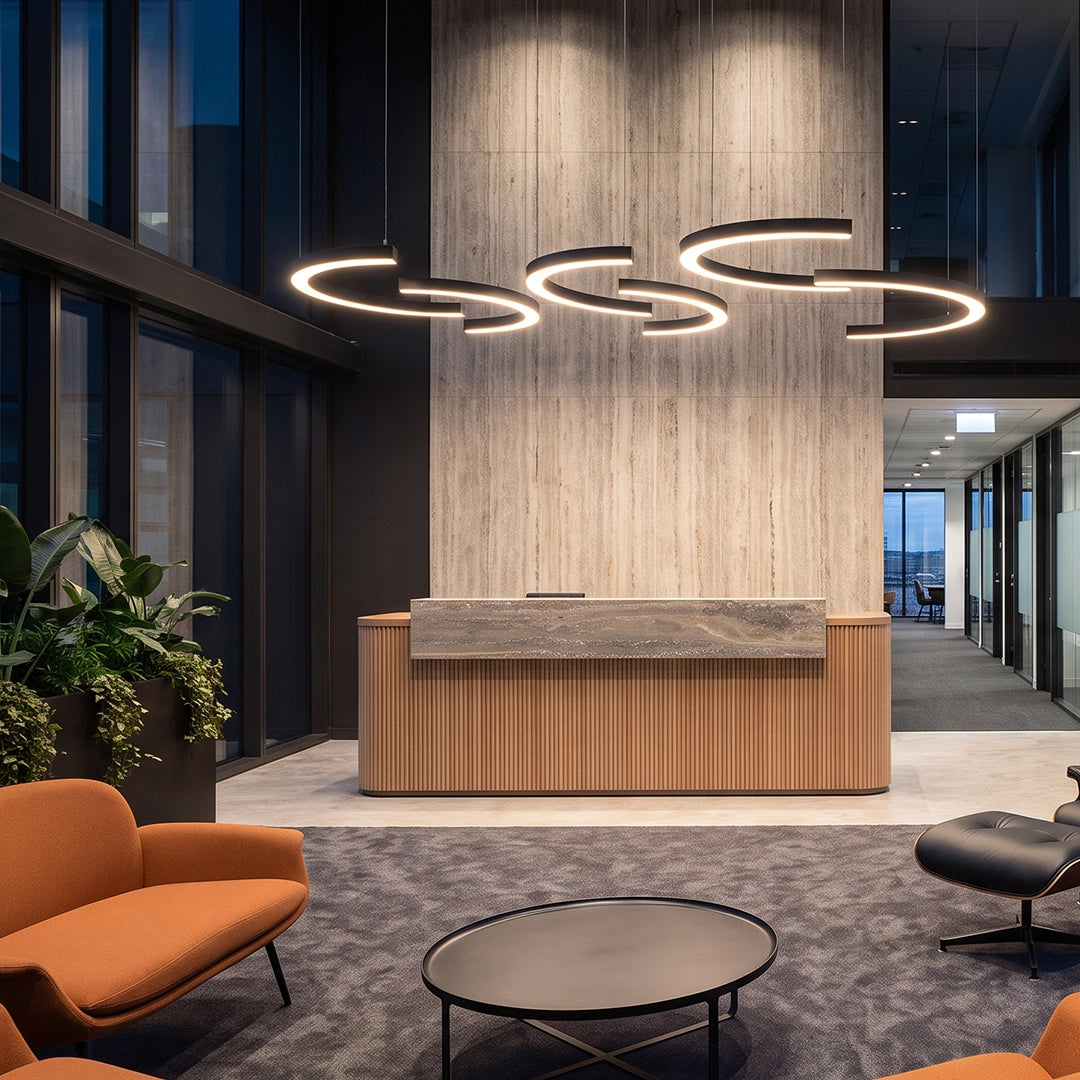 C shape pendant light in a modern office lobby, featuring multiple suspended LED ring segments above a wood reception desk.