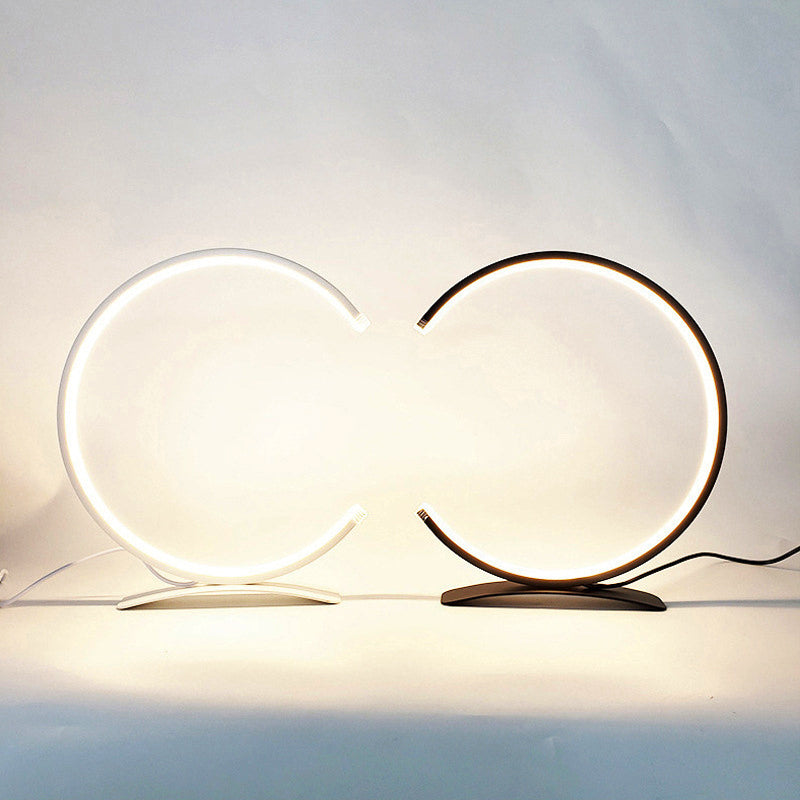 C shaped table lamp enhancing a minimalist desk with elegant, curved design.