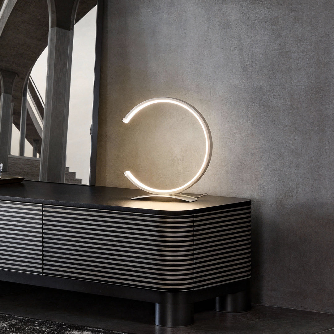 C shaped table lamp providing soft light beside a stylish dresser.