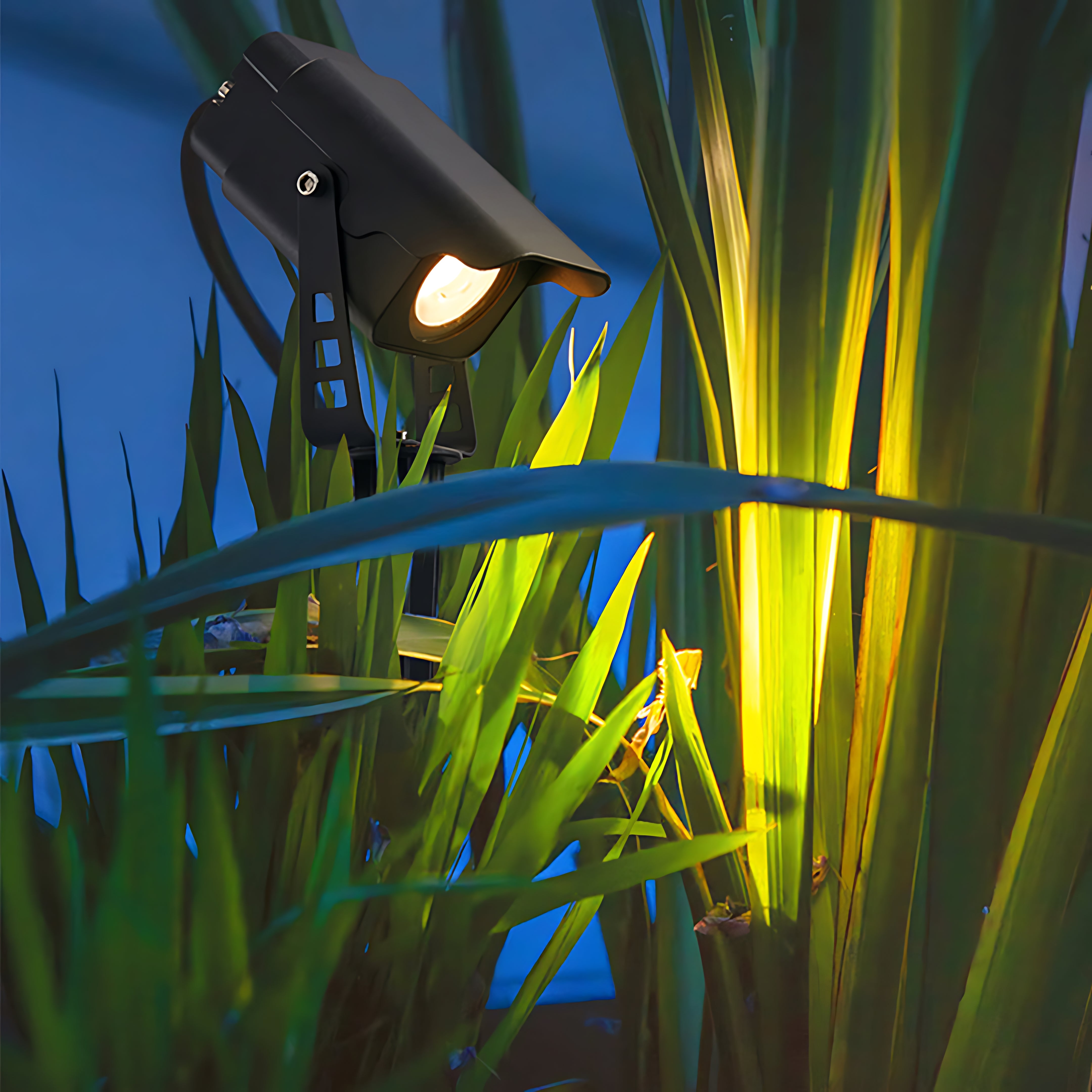 Landscape spotlight illuminating tropical plants with dramatic yellow and green lighting effect