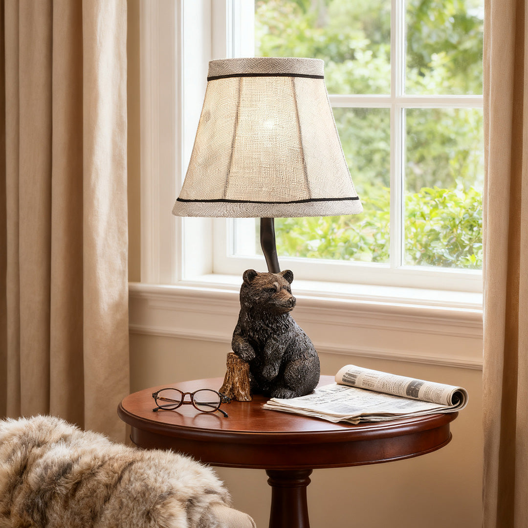 Cabin-style resin table lamp providing warm ambient light on a round table near a window, perfect for reading.