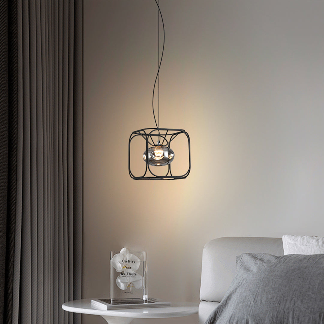 Single caged pendant light with black wire frame suspended beside a bed, creating a soft and comfortable indoor lighting mood.