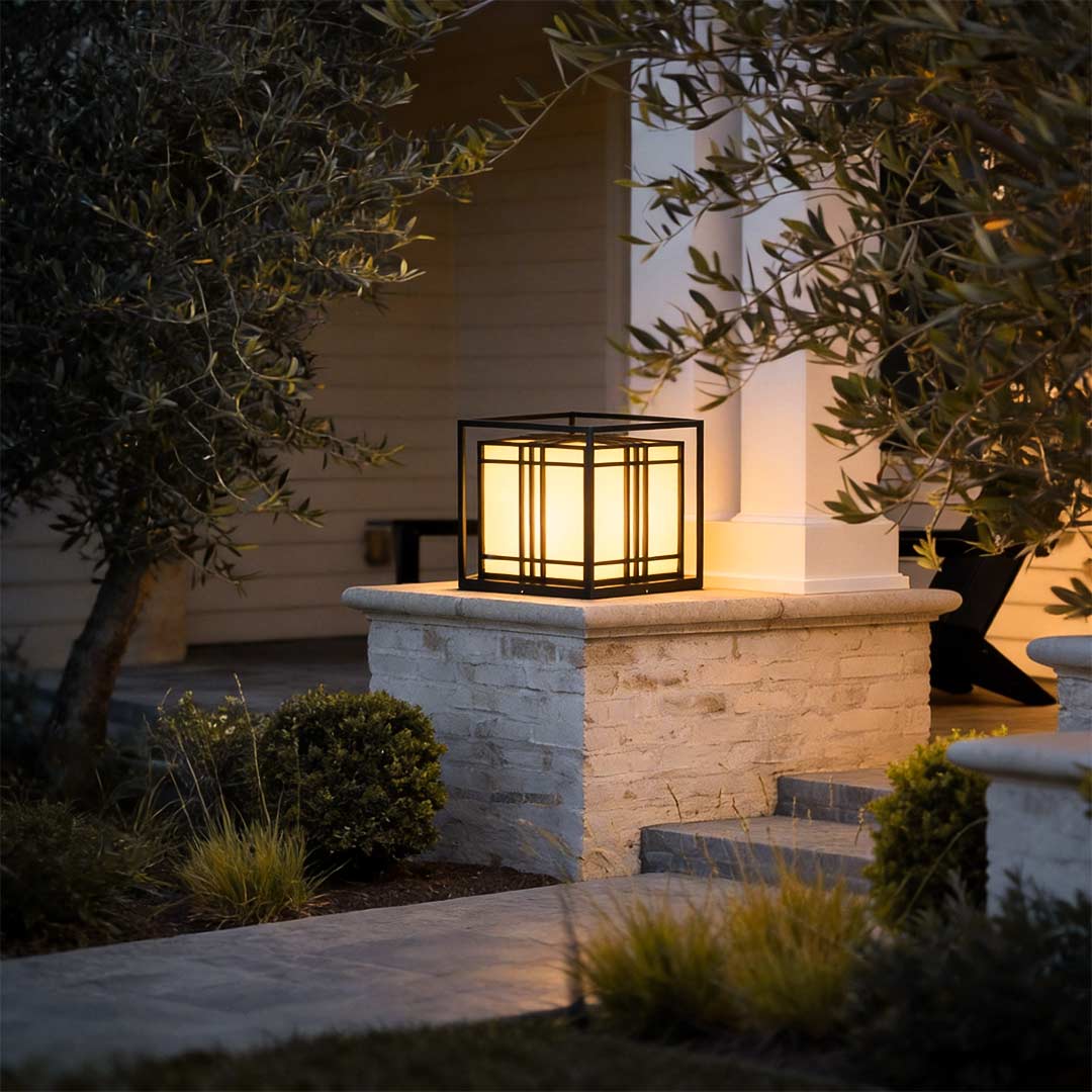 Caged pillar lights illuminating a modern garden pathway with warm directional glow.