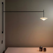 Minimalist black cantilever wall lamp extending over a table, creating warm ambient light in a modern interior.