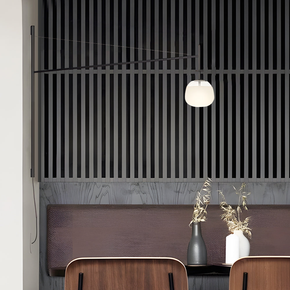 Elegant cantilever wall lamp with spherical diffuser illuminating a dining area in a refined modern interior.