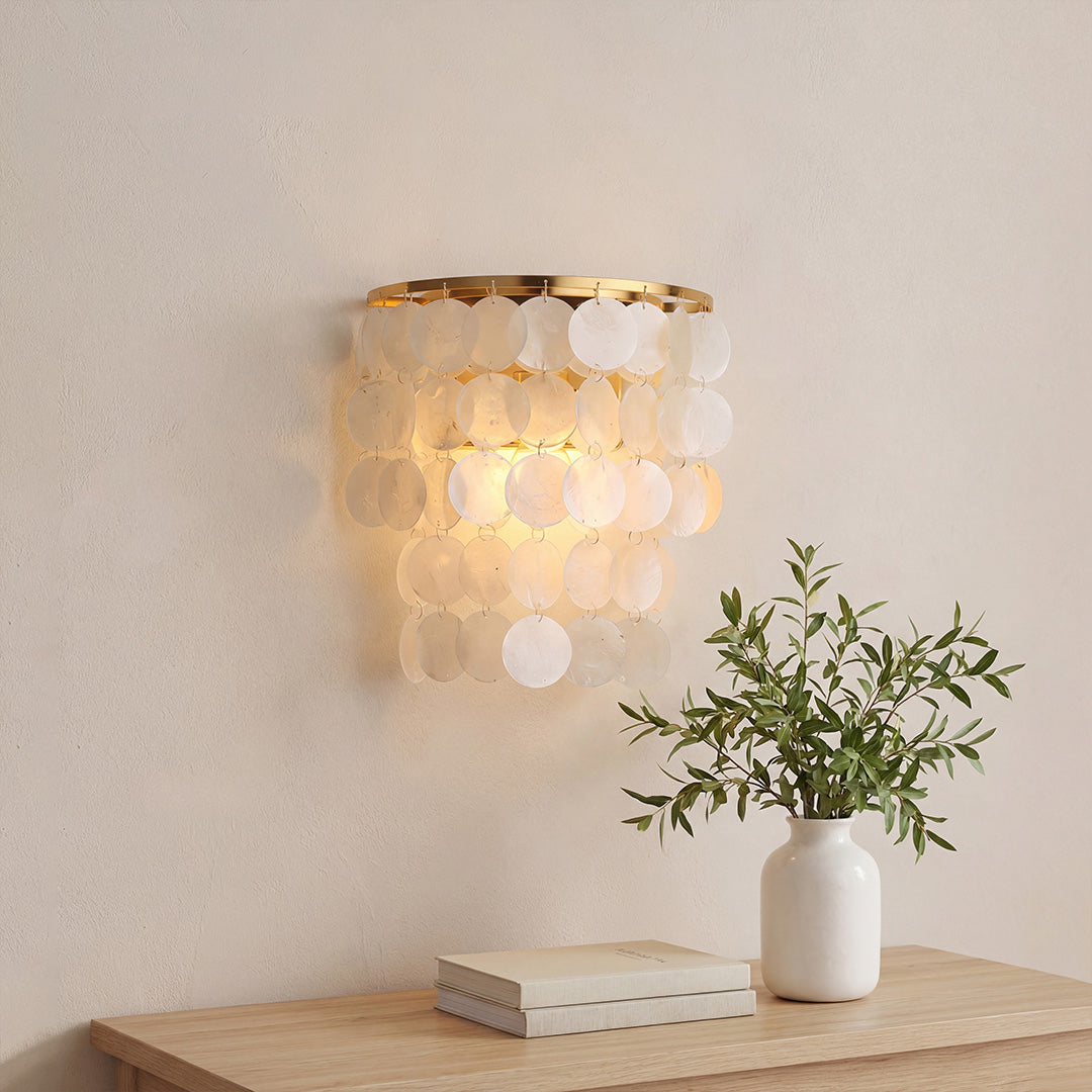 Modern gold capiz shell wall sconces with tiered translucent discs on a textured interior wall.