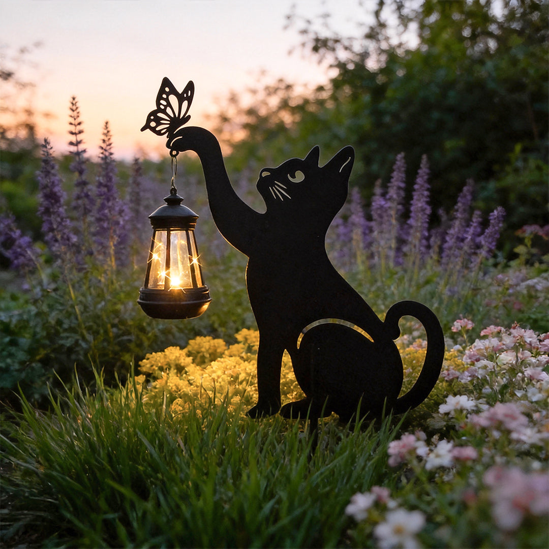Cat silhouette light providing soft illumination among flowers and plants.