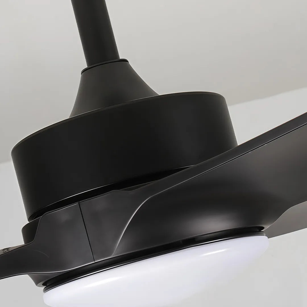 Close-up of a ceiling fan with light showing the matte black motor housing and integrated LED diffuser.