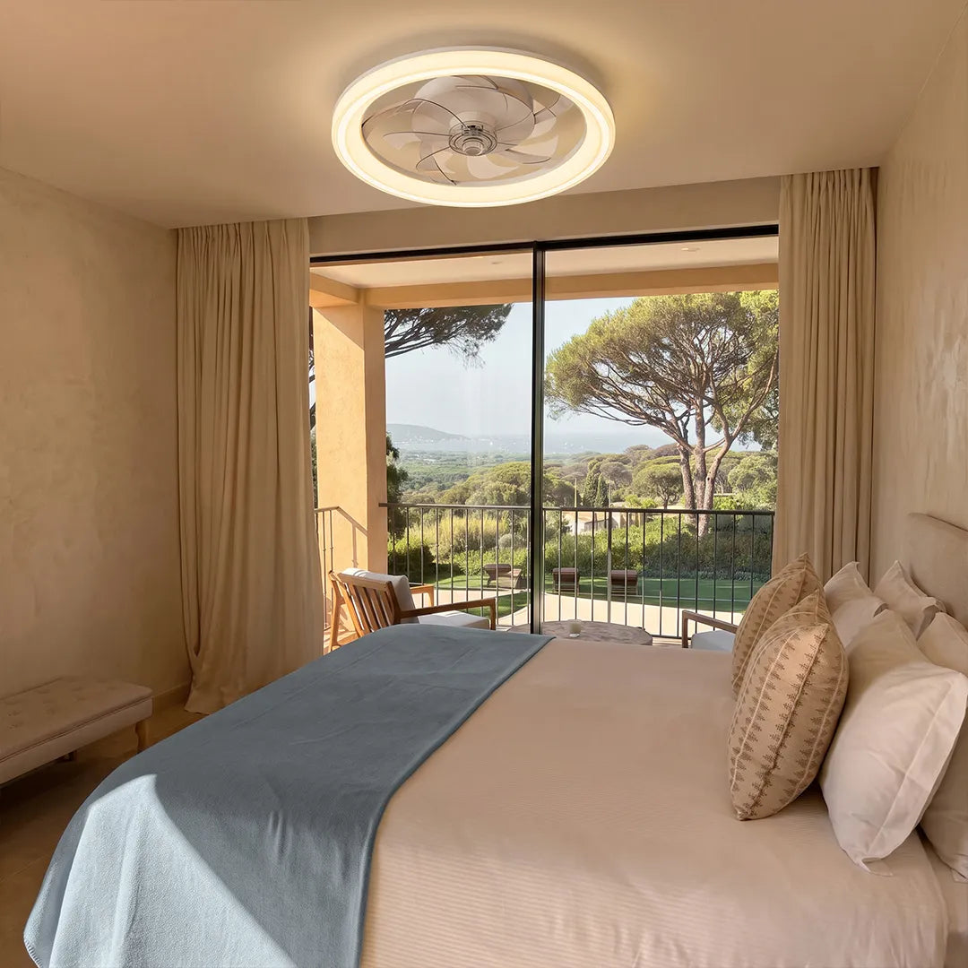 Ceiling fans with light fixtures installed above a bed in a bright bedroom with large windows and neutral decor.