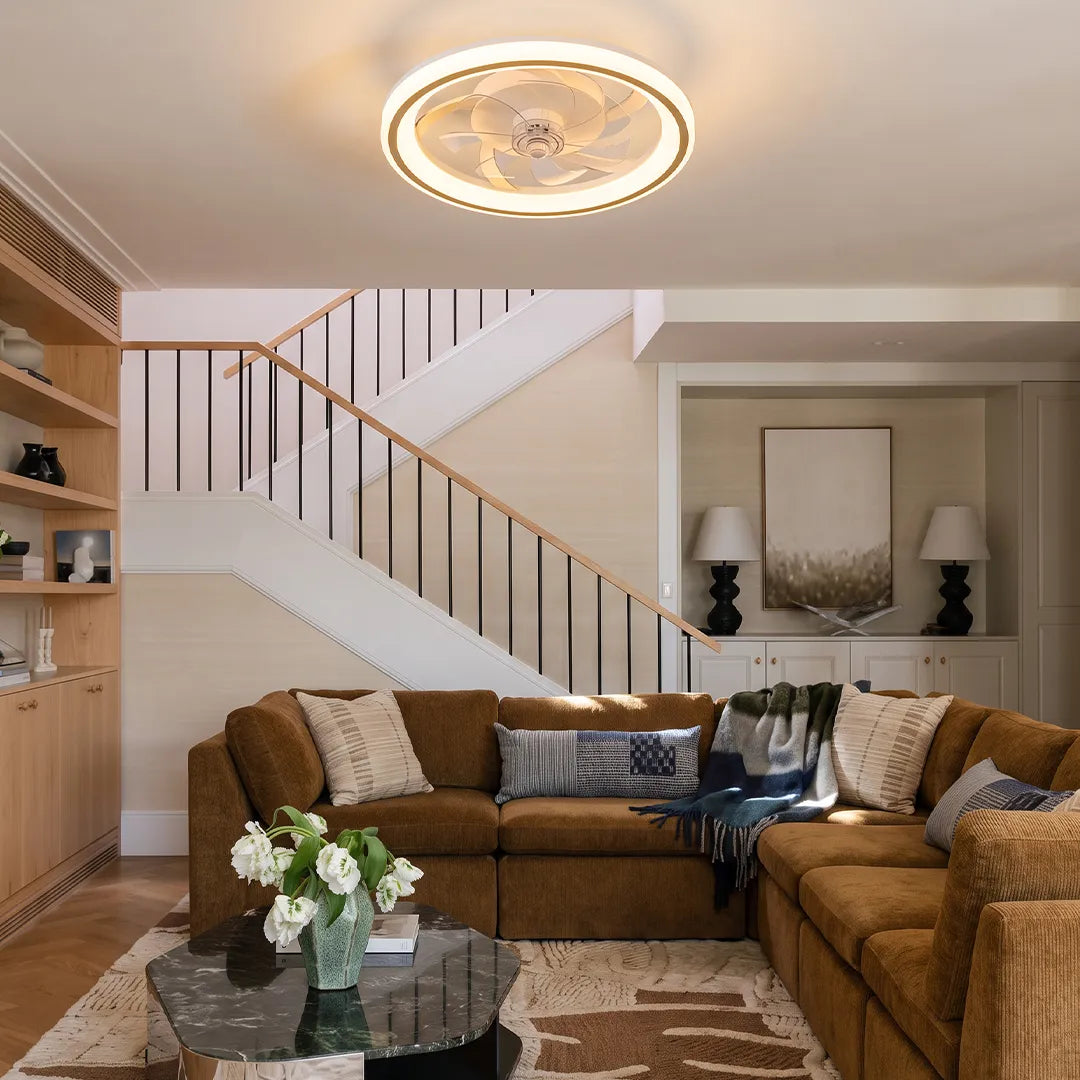 Ceiling fans with light fixtures mounted above a sectional sofa in a contemporary living room with a staircase.