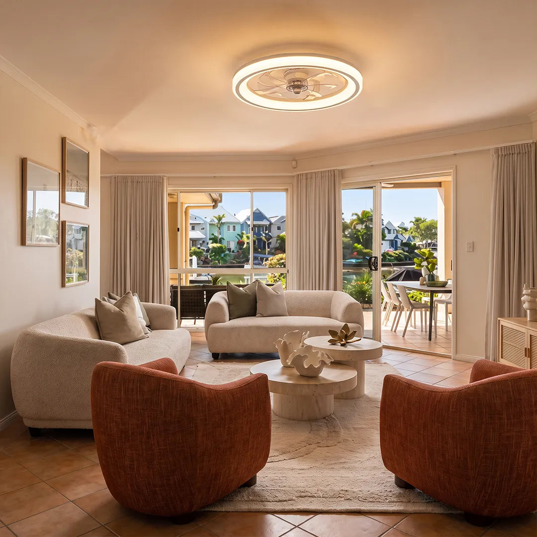 Ceiling fans with light fixtures illuminating a spacious living room with large windows and modern seating.