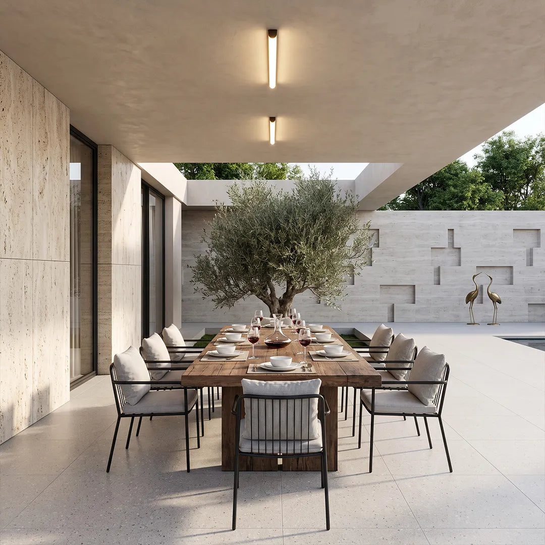 Ceiling linear lights illuminating a modern covered patio dining area with a concrete ceiling.