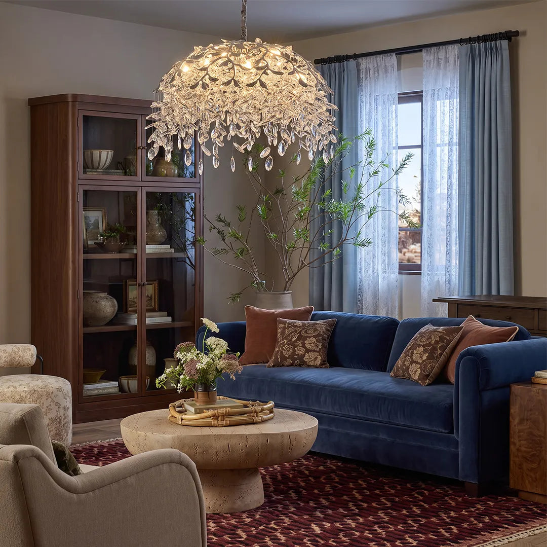 Chandelier with crystal suspended above a blue sofa in a cozy living room with layered neutral decor.
