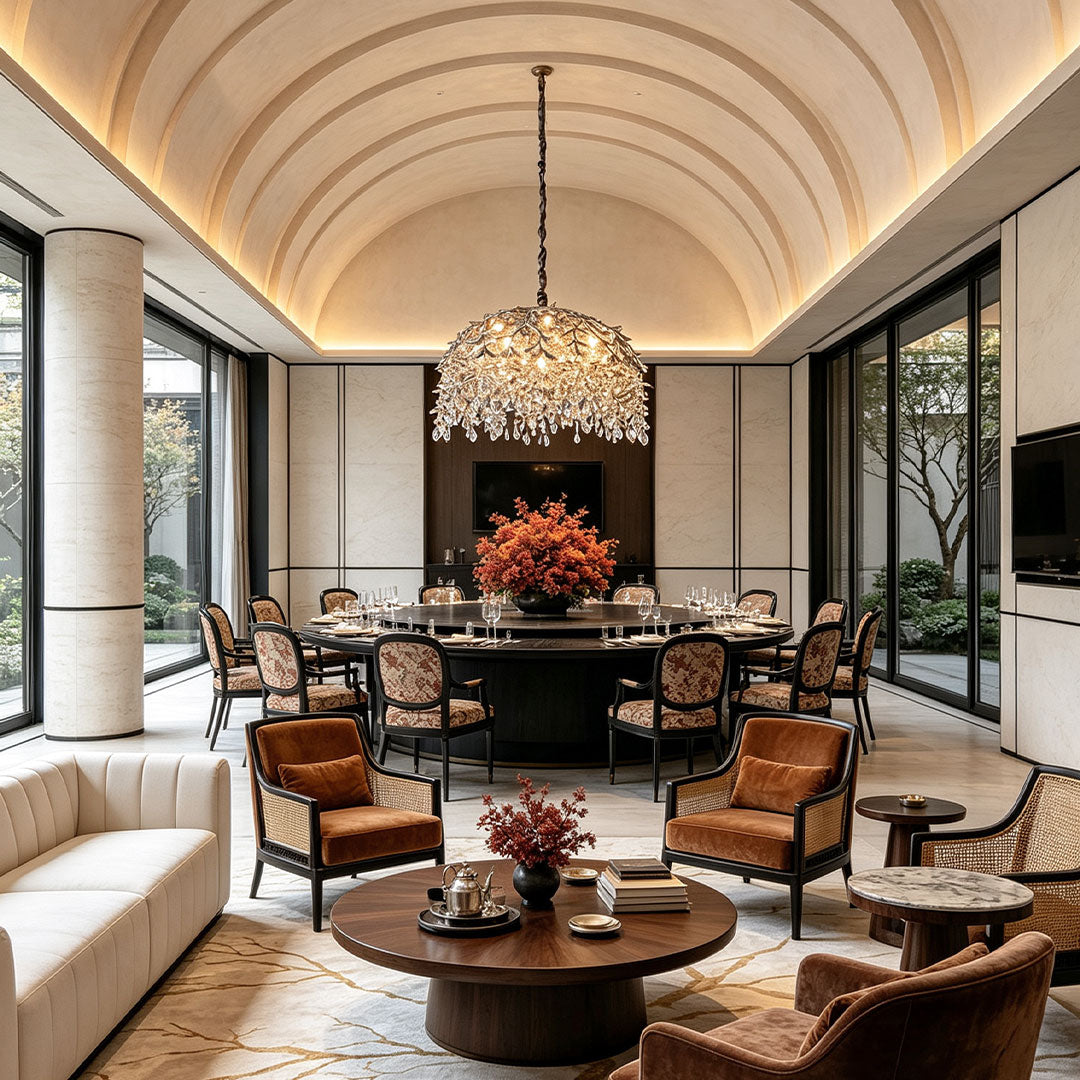 Chandelier with crystal centered above an elegant lounge and dining area with a curved ceiling and warm ambient lighting.