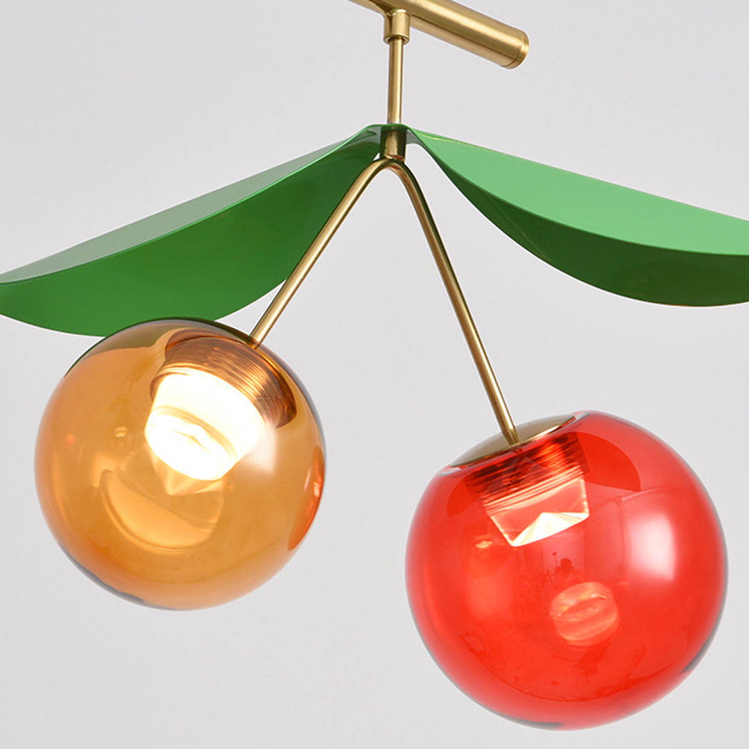 Close-up detail of cherry pendant light showing glossy red and golden glass spheres with brass hardware